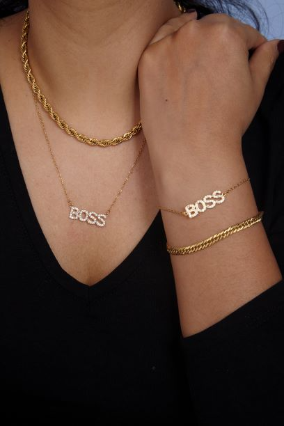 Goldene Edelstahlkette und Armband mit "BOSS"-Schriftzug, getragen an Hals und Handgelenk, gedrehte Gliederoptik