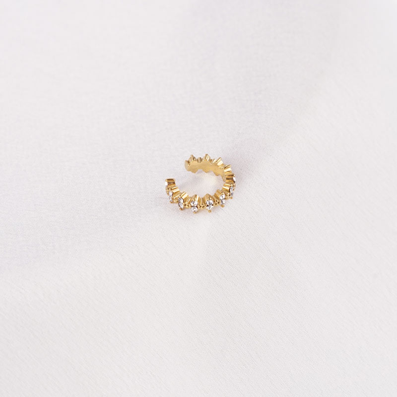Goldfarbener Edelstahl-Earcuff mit spitzen Details und funkelnden Steinen auf hellem Hintergrund