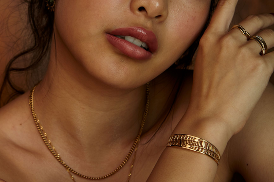 Edelstahlkette in Goldoptik, runde Glieder, getragen von Frau mit passendem Armband und Ringen