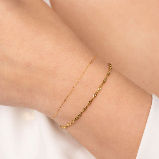 Goldfarbenes Spiral Links Edelstahl Armband am Handgelenk, filigranes Design, glänzende Oberfläche