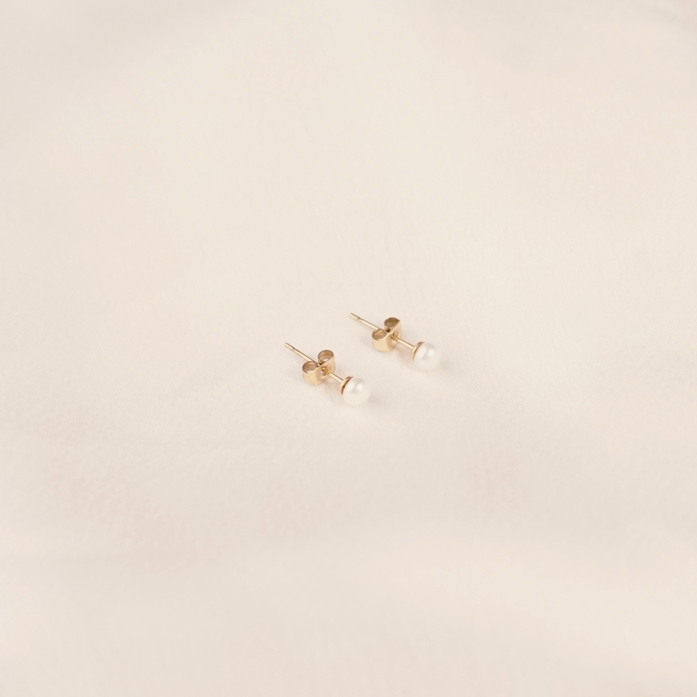 Edelstahl-Ohrringe mit Süßwasserperlen, goldfarben, minimalistisch, auf hellem Hintergrund