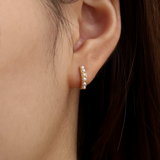 Goldfarbener Edelstahl-Ohrring mit kleinen Perlen, kreisförmig, am Ohr getragen