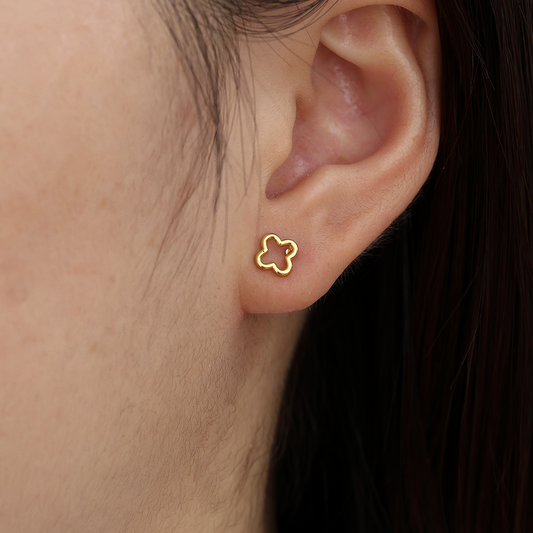 Goldfarbene Edelstahl-Ohrringe in Kleeblattform, hohles Design, am Ohr getragen