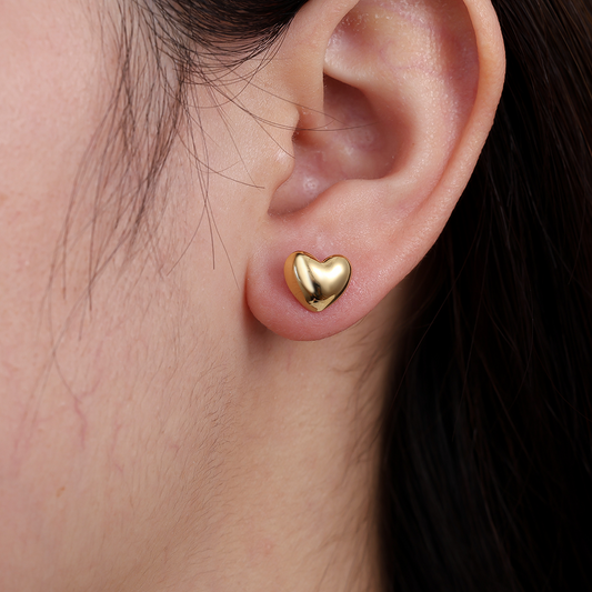 Goldfarbener Herz-Ohrstecker aus Edelstahl am Ohr getragen, glänzende Oberfläche