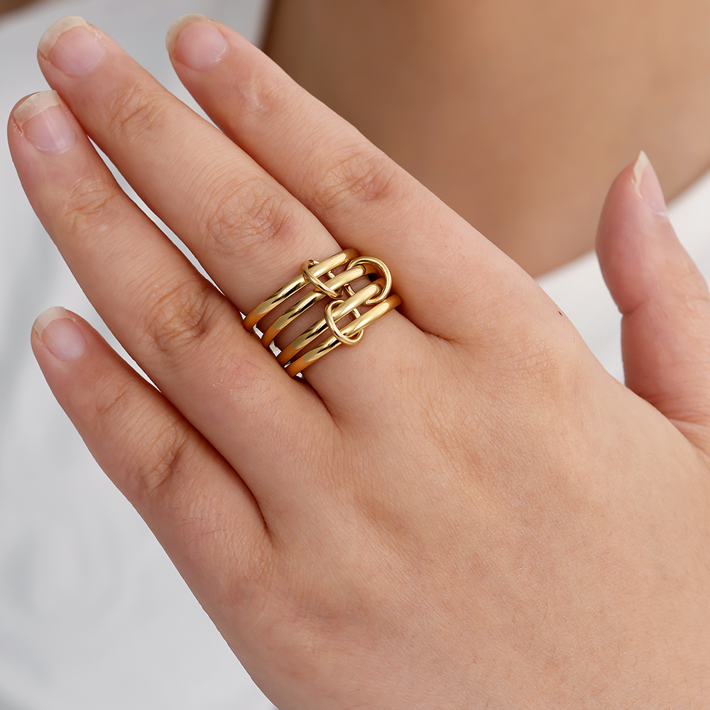 Goldfarbenes Edelstahl-Ringset mit mehreren schlichten Ringen, getragen auf einer Hand, ineinander verschlungenes Design.