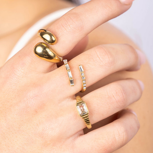 Goldfarbener Edelstahlring mit geschwungenem Design, getragen an der Hand.