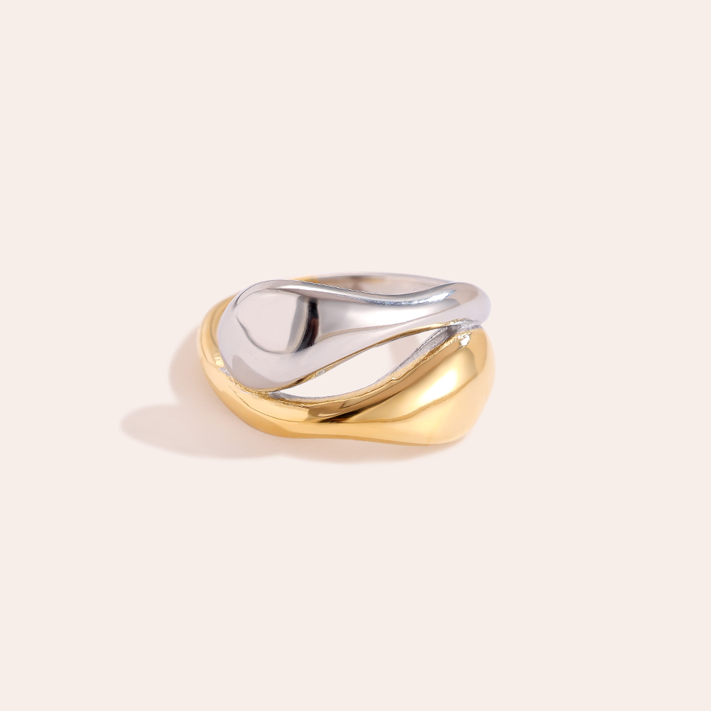 Zwei ineinander verschlungene Edelstahlringe, einer in Gold, der andere in Silber, mit geschwungenem Design.