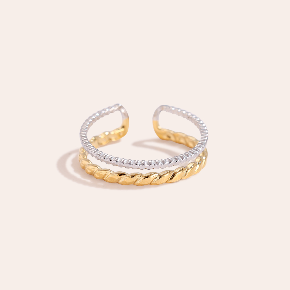 Zweischichtiger Edelstahlring, gedreht, in Gold und Silber, offene Form, feine Struktur.