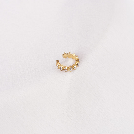 Goldfarbener Edelstahl-Earcuff mit spitzen Details und funkelnden Steinen auf hellem Hintergrund