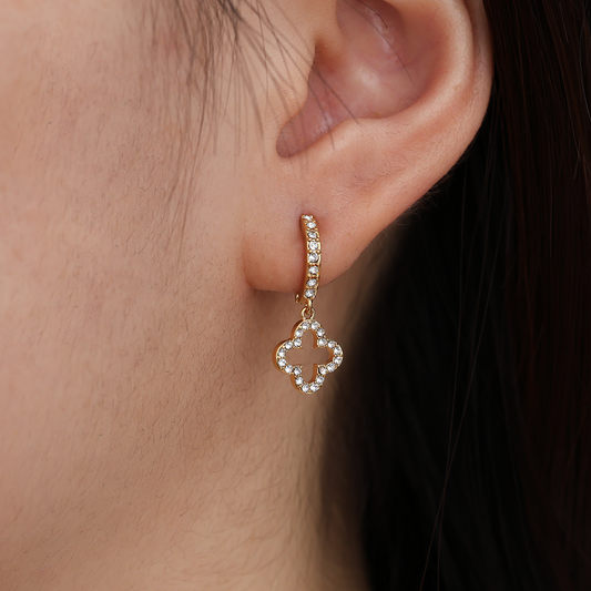 Edelstahl-Ohrring mit diamantbesetztem Kleeblatt-Anhänger, goldfarben, am Ohr getragen