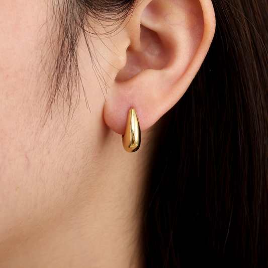 Goldene Drop Hoop Ohrringe aus Edelstahl am Ohr getragen, glänzende Oberfläche, tropfenförmiges Design