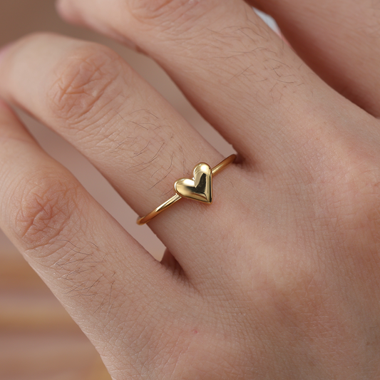 Goldfarbener Edelstahlring mit Herzmotiv auf Finger getragen