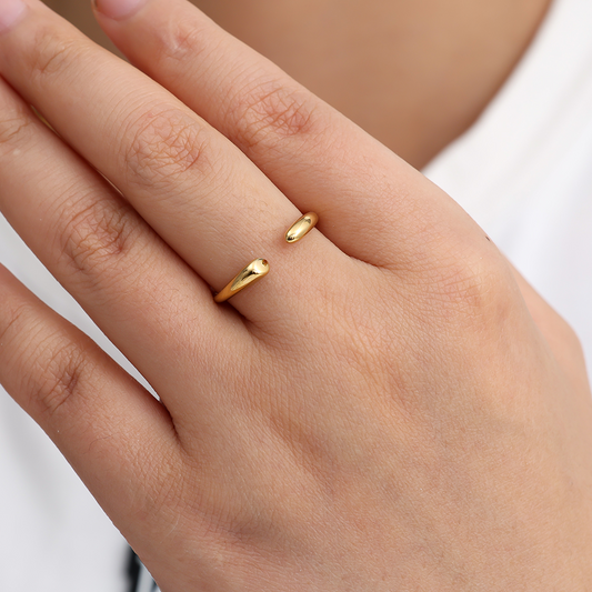 Goldfarbener Edelstahlring mit offenem Design, getragen an einem Finger einer Hand