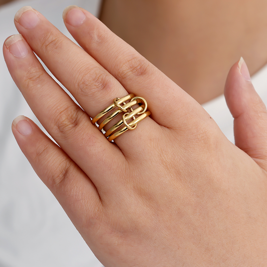 Goldfarbenes Edelstahl-Ringset mit mehreren schlichten Ringen, getragen auf einer Hand, ineinander verschlungenes Design.