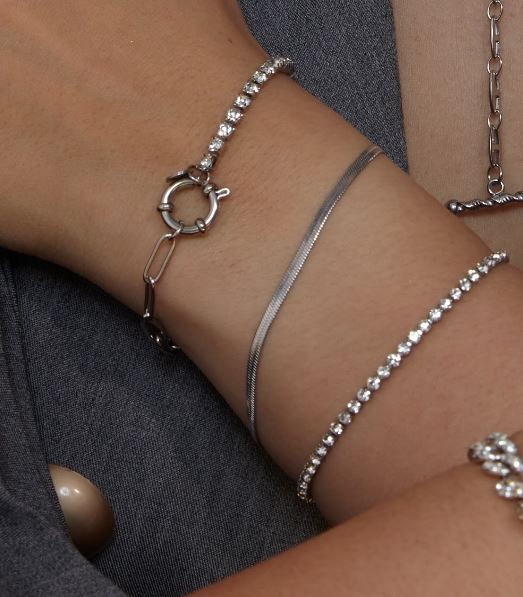 Edelstahlarmband mit feinen Tennis-Designs, silberfarben, auf Handgelenk getragen, kombiniert mit anderen Armbändern